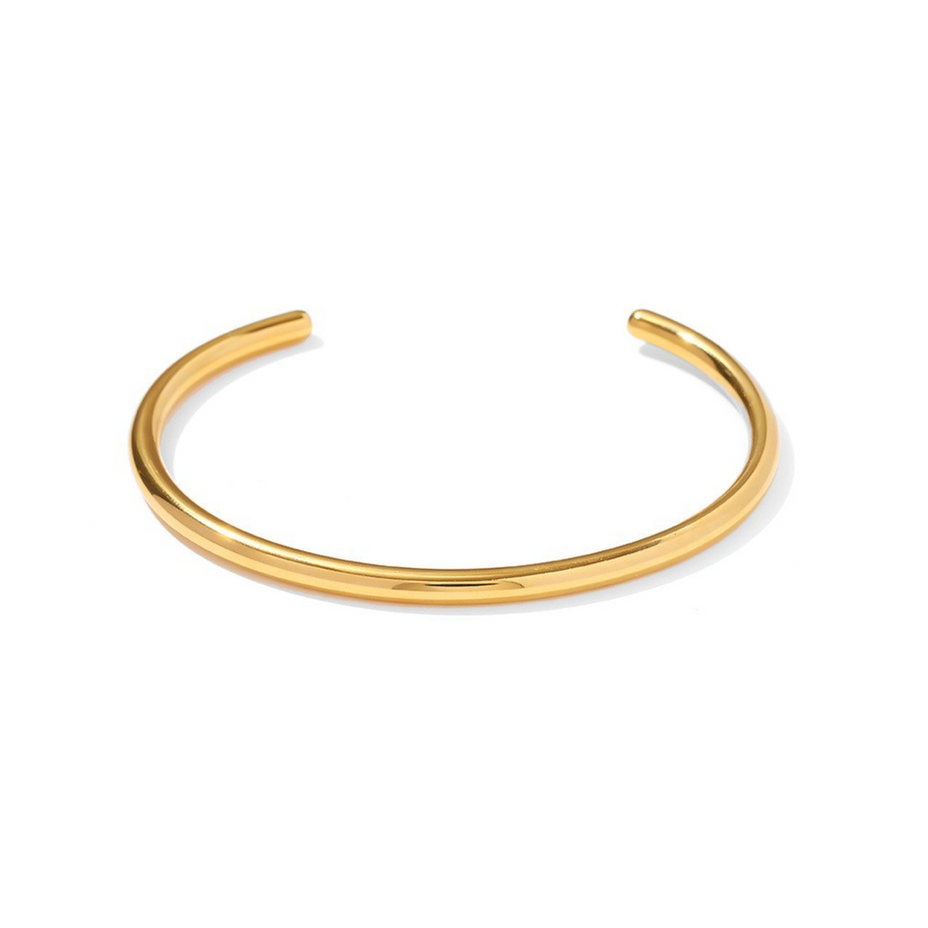 Pulseira cuff dourada escultural com design minimalista e linhas arquitetónicas.