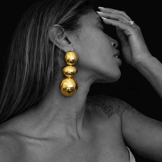 Brincos longos dourados com design de esferas em modelo, contraste preto e branco