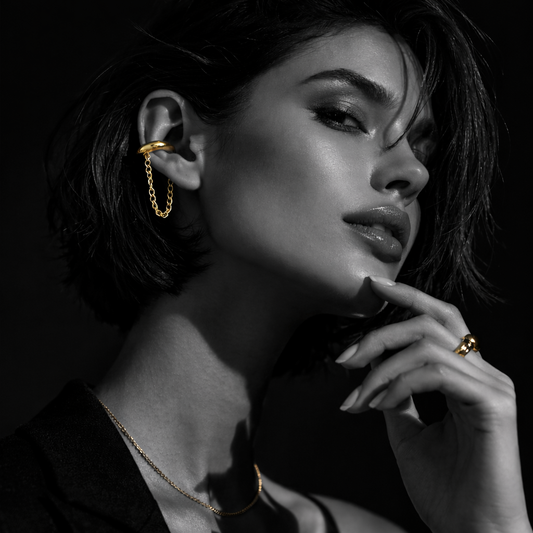 Modelo a usar earcuffs dourados Nova com corrente em styling urbano minimal.