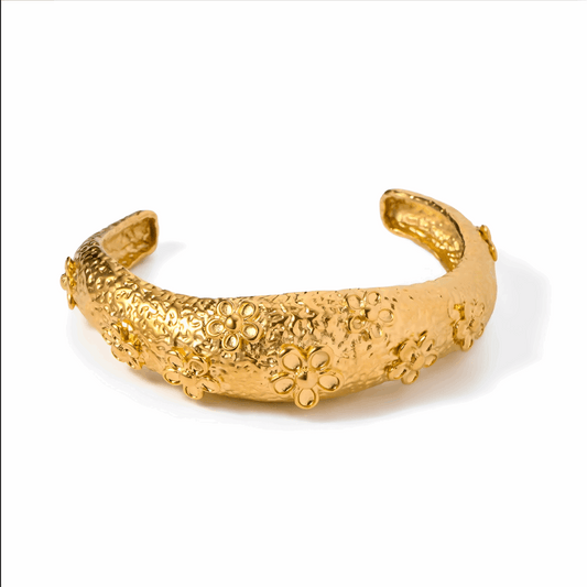 Pulseira Mia dourada com design texturizado e detalhes florais em relevo, fabricada em aço inoxidável.