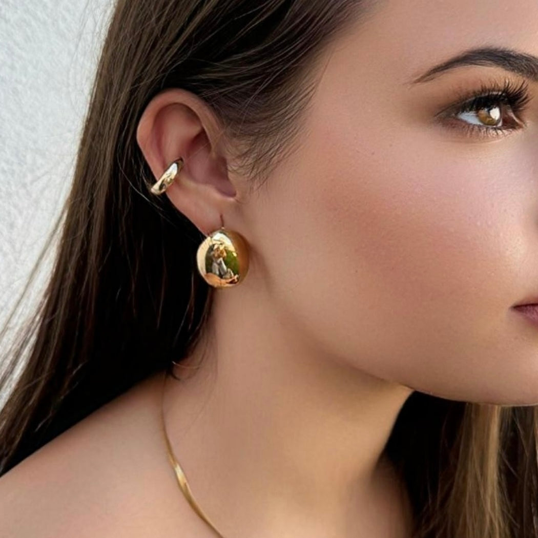 Modelo a usar os brincos Maris em dourado, com estilo clássico e elegante.